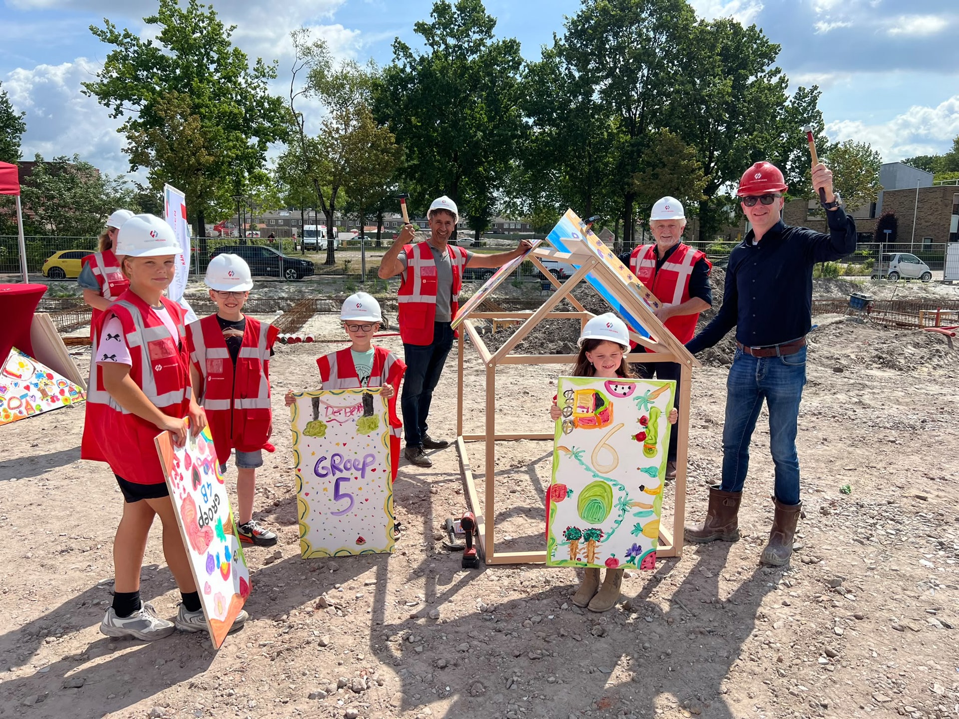 De kinderen staan samen met de directeuren bij het versierde huisje